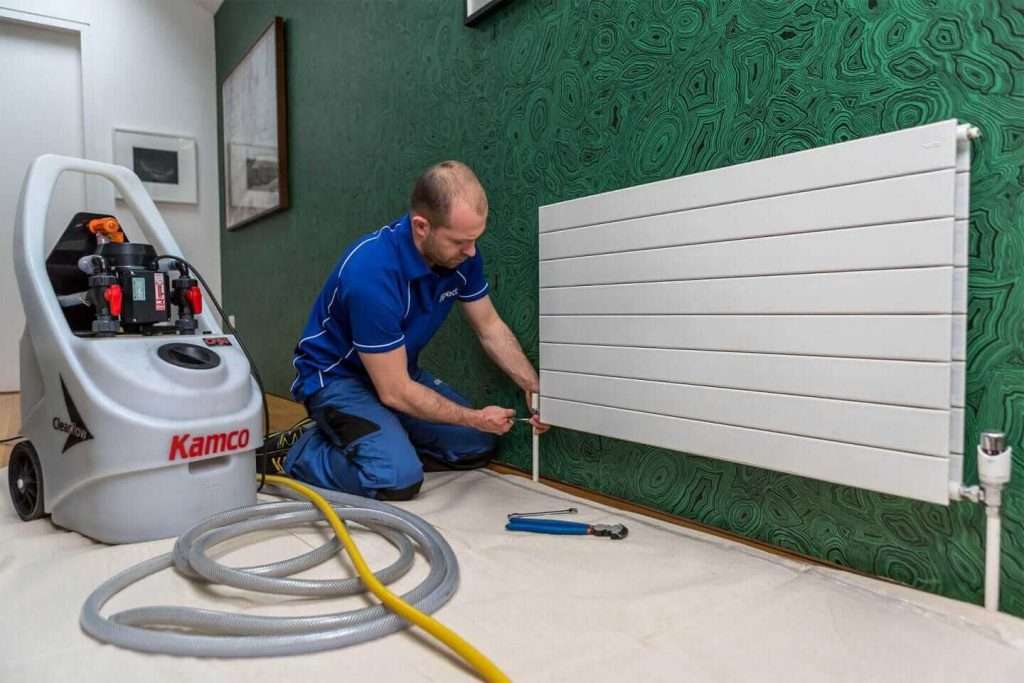 Power flush cleaning process for central heating system removing sludge and debris from pipes and radiators.